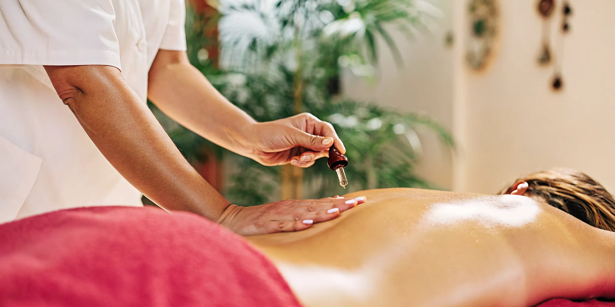 Massage therapist applying CBD oil to guest's back during therapeutic session