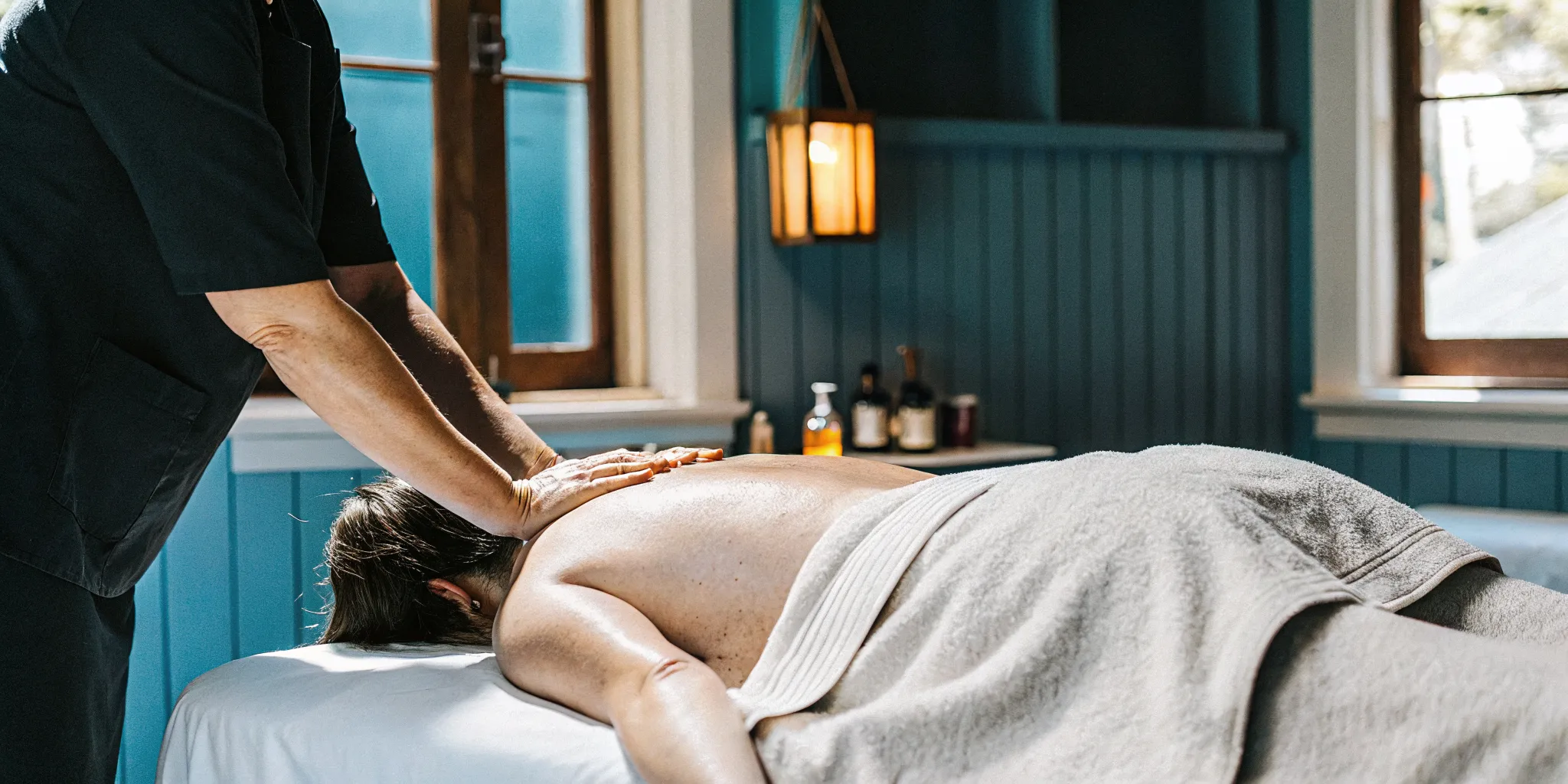 Massage therapist performing deep tissue back pain relief techniques on a guest in a warm New Orleans studio