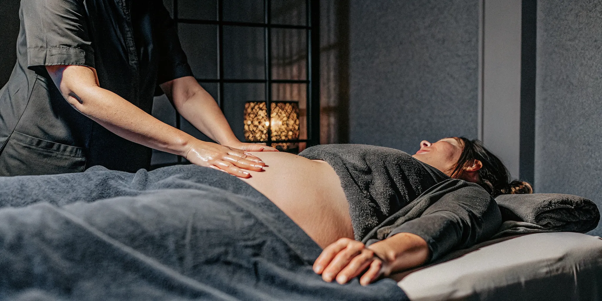 Peaceful pregnant woman receiving prenatal massage in a warm New Orleans studio with proper side-lying positioning